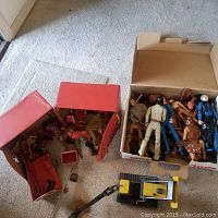 Wide view of toy storage boxes containing multiple vintage Marx Best of the West action figures and a Tonka yellow bulldozer on carpet.