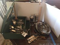 Photo showing collection of silver plated flatware, a green leather lined box containing utensils, two goblets, a tall cup and a large tray with lid.