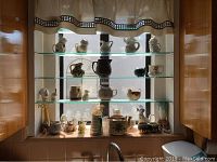 Shelf with multiple shelves displaying about 40 ceramic decorative items including small pitchers, animal figurines, and vessels.