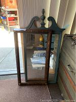 Wooden picture frame with carved details leaning against a window, showing front view.