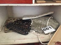 Four vintage 1920s evening purses with intricate bead and sequin detailing inside a white shelf.