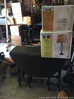Drop leaf gate table with two boxed lamps stacked on top, placed in a garage setting with shelves and boxes