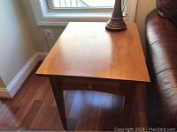 Overview of one wooden side table showing the top surface, single drawer, and wooden knob.