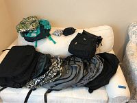 Full view of all items arranged on a white couch showing backpacks, computer bags, and pouches containing reusable bags
