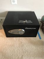 Front view of black SentrySafe safe with silver electronic keypad and handle, sitting on carpet.