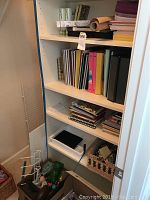 Shelf with assorted school supplies including notebooks, binders, chemistry kits, rolled paper, and desk organizer items.