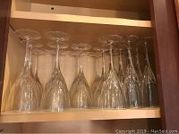 Eighteen clear Waterford crystal wine glasses arranged upside down in a cabinet.