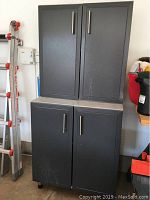 Front view of the stacked storage cabinets showing two-door design and metal handles.