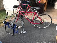 Wide view showing red Crossroads Cruz road bike, Blackburn hand pump, and Thule bike rack on asphalt.