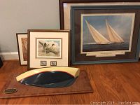Photo showing all framed art pieces arranged on floor with mounted yacht model in front