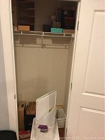 Closet with plastic storage containers and some cigar boxes on floor and bottom shelf