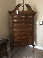 Full view of highboy chest showing broken arch pediment, finial, upper and lower drawers, cabriole legs