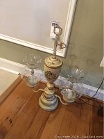Front angled view of a 22 inch tall antique style table lamp, showing beige and gold base with two clear glass shades.