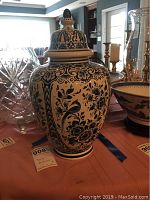 Delft ginger jar with blue floral design on white porcelain, standing on an orange tablecloth, showing the full jar with lid