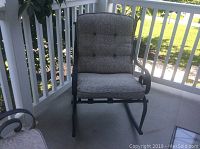 Front view of a metal rocking chair with cream patterned cushion