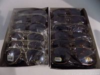 Two boxes containing 24 pairs of driving sunglasses in plastic packaging, different aviator styles visible.