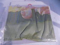 Silk scarf laying partially folded showing floral pattern with green, pink, yellow, and beige colors.