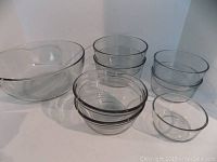 Lot of 8 glass bowls arranged in a group showing sizes, including 1 XL bowl and 7 smaller Anchor Hocking bowls.