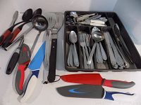 Overall view of the assortment of knives with colorful handles, serving utensils, and utensils tray.