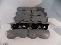 Ten Suntuff sunglasses arranged with their matching gray hard cases stacked behind them.