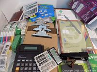Photo showing calculators, clipboards, colored pens, sticky notes, report covers, and other assorted office supplies.