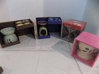 Overview of four boxed candle diffusers of various colors and styles, showing each in original packaging.