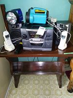 Full view showing stereo with speakers on wooden table, two Uniden cordless phones, and three flashlights visible on top