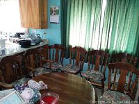 Dining area showing round wooden dining table surrounded by six matching wooden dining chairs with floral seat cushions and two larger captain chairs at the ends.