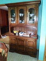Frontal view of the wooden buffet and hutch, showing the upper hutch with glass pane doors and lower buffet with solid panel doors.