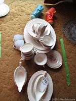 Tea cups, saucers, and platter stacked together showing floral pattern.