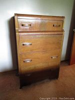 Front view of waterfall style highboy dresser showing four drawers with wooden handles, visible wear and one detached handle area.