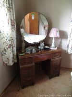 Front view of the vanity and round mirror with some items on top.