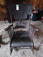 Front view of antique wooden rocking chair showing carved backrest and spindle details.
