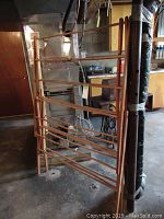 Photo showing wooden drying rack folded and standing vertically in basement storage area.