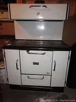 Front view of Findlay Condor wood stove showing white metal body with black top and chrome handles.