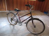 Full view of the maroon Raleigh ladies 5-speed bicycle showing frame, wheels with flat tires, saddle, fenders, and rear rack