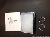 Pair of silver hoop earrings next to their black textured box.