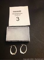 Pair of twisted design .925 sterling silver hoop earrings displayed alongside auction card.