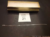 Photo of 925 silver ankle bracelet laid out flat with clasp visible and decorative storage box open beside it.