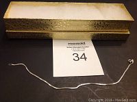 Silver ankle bracelet laid out with a detailed rectangular jewelry box behind it.