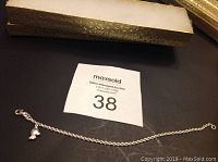 Silver chain wrist bracelet laid out with clasp and small turtle charm visible.