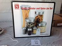 Photo of the Cook Home branded box showing the 8-piece glass canister and spice jar set with clear glass and silver lids.