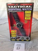 Front view of boxed Pro-4 Power Tactical Survival Watch showing brand, model, and key features like glow in the dark, adjustable band, shock and water resistance.