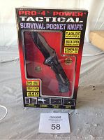Front view of the Pro-4 Power Tactical Survival Pocket Knife in box, showing knife through packaging and feature highlights.