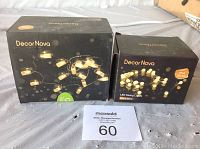 Two boxed sets of Decor Nova warm white LED string lights shown side by side with auction lot number.