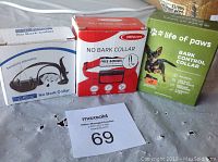 Three different boxed no bark dog collars arranged side by side on a surface.