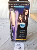 Purple Infiniti PRO by Conair 2-in-1 hair styler in original packaging showing tourmaline ceramic plates, 360°F ultra-high heat, and dual functionality as straightener and curler.