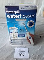 Box front showing Waterpik Water Flosser ULTRA, ADA accepted, 6 tip types included, and benefits for healthier gums