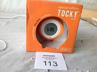Front view of the special edition TOCKY Touch alarm clock inside original orange box with visible round digital display showing 5:00 time.
