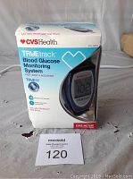Photo of TrueTrack Blood Glucose Monitoring System in original box showing the device screen and product branding.